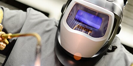 Metalworker welding and using a 3M welding helmet for protection
