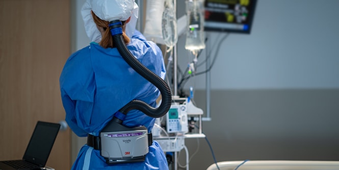 Clinician wearing a powered air-purifying respirator
